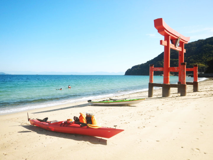 A photo of a kayak and Torii gate on a beach